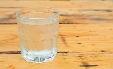 Glass water with ice,Drops water on glass,wooden table.