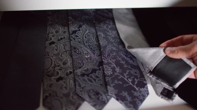 Close up on hand picking out a neck tie in a man's clothing shop