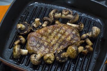 Cooking steak and mushrooms on the grill pan