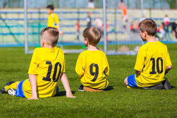Group Of Young Boys Wearing Sport Outfit. Youth Soccer Players sitting on sports venue.