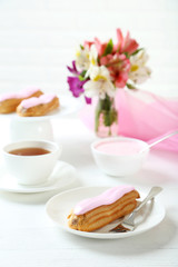 Eclairs with glaze on a white wooden table