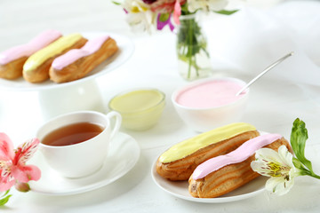 Eclairs with glaze on a white wooden table
