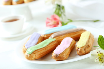 Eclairs with glaze on a white wooden table