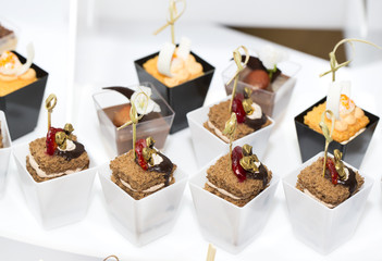 mini canapes in plastic cups decorated with edible flowers