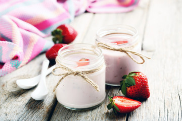 Strawberry yogurt in glass on a grey wooden table
