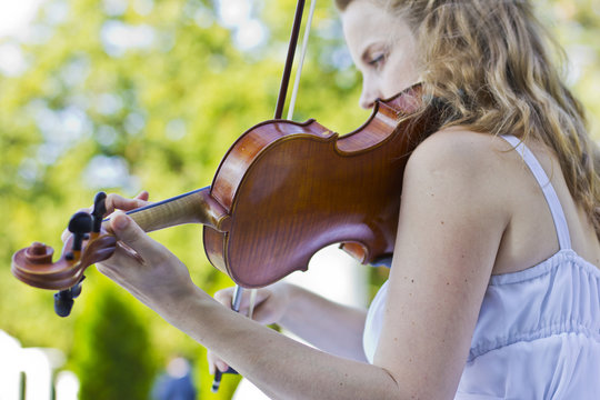 Girl playing on the violin outdoors. Musician for the wedding.Violin under the open sky
