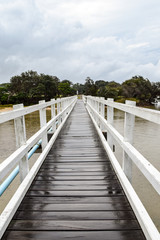 White timber pedestrian bridge crossing on an overcast and drizzly day - no people