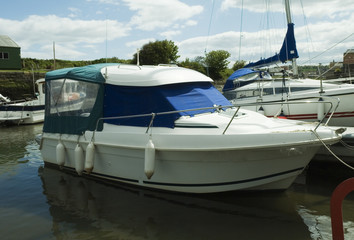 a white motor boat covered with tarps and docked 