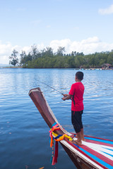 man angle fish on wooden boat in river