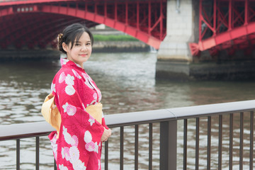 Asian woman wearing red kimono walking on a bridge