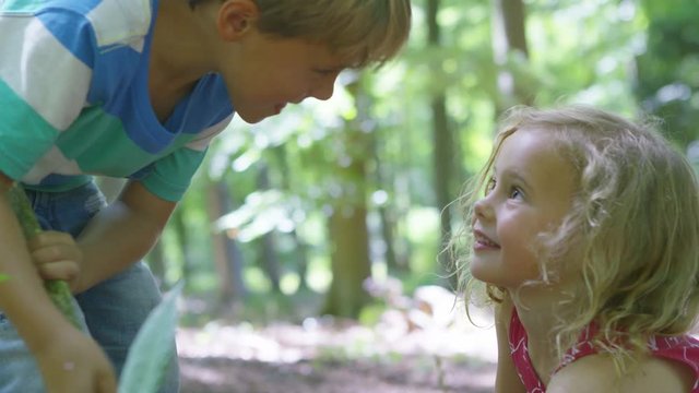  Happy little boy & girl playing in the woods & looking for insects