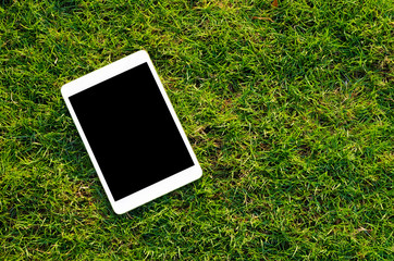 Digital tablet on the green grass