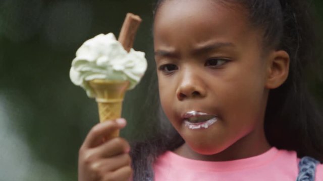  Portrait of African American brother & sister enjoying ice creams in the park. 