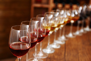 Many glasses of different wine in a row on bar counter