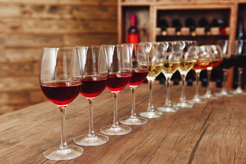 Many glasses of different wine in a row on bar counter