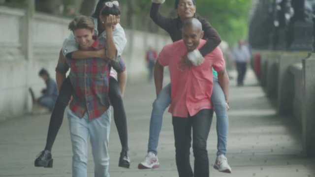  Happy energetic group of friends in London, playing piggyback races