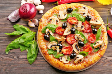 Delicious tasty pizza with ingredients on wooden table