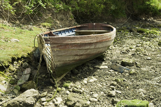 old rowing boat sitting abandoned on a pebble beach