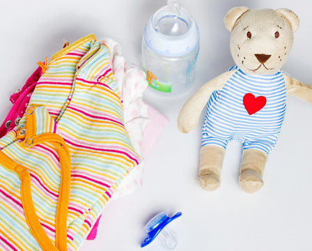 A stack of children's clothing, toys, pacifier on a white backgr