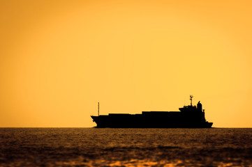 Obraz premium Silhouette of cruise ship at sunset in a sea