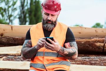 Worker in overalls and with a tattoo are checking the quality of materials and other inspections, makes recording on your mobile phone