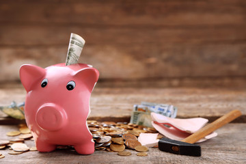 Broken piggy bank with cash and coins on wooden background