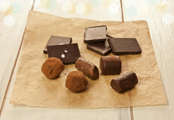 Chocolate bonbons and pieces on cooking paper with blurred background