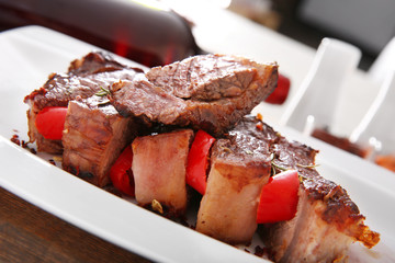 Sliced roasted pork steak with bottle of red wine on white plate