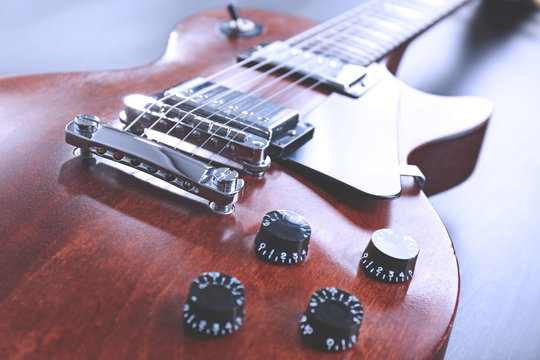 Brown electric guitar on black wooden background, close up