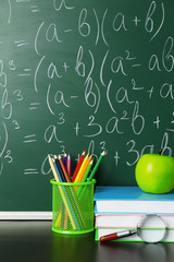 School books on desk near chalkboard