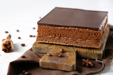 Delicious chocolate cake on wooden cutting board closeup