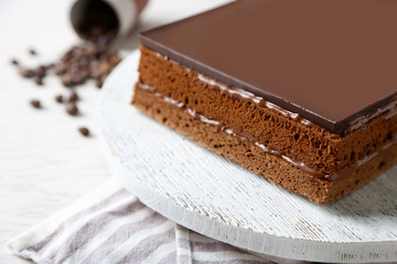 Delicious chocolate cake on wooden cutting board closeup