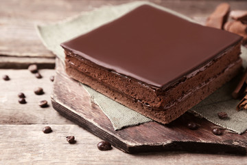 Delicious chocolate cake with coffee beans on wooden background