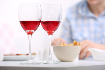 Dinner with glasses of wine on light blurred background
