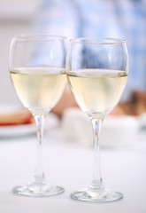 Dinner with glasses of wine on light blurred background