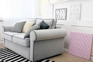 Modern interior with sofa and pictures on shelves in room