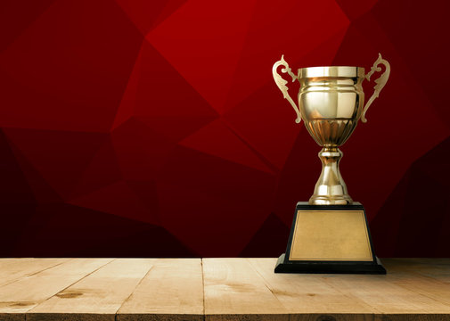 golden trophy on wood table with Red White Polygonal Mosaic Back