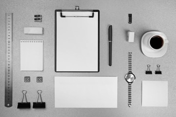 Office set with white sheets of paper, cup of coffee, watch and stationery on grey background