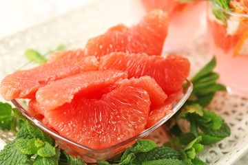 Juicy grapefruit pieces with fresh mint in a bowl, close up