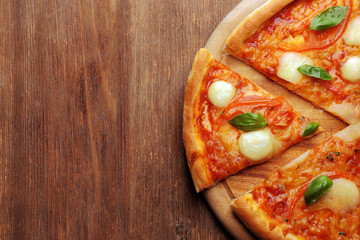 Sliced Margherita pizza on wooden background