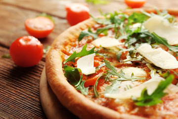 Margherita pizza with tomatoes, Parmesan and arugula on wooden background