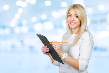 blonde businesswoman writing notes in the clipboard