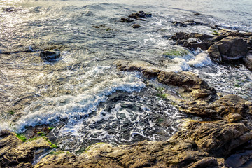 wave rolls onto the rocks of sandy coast