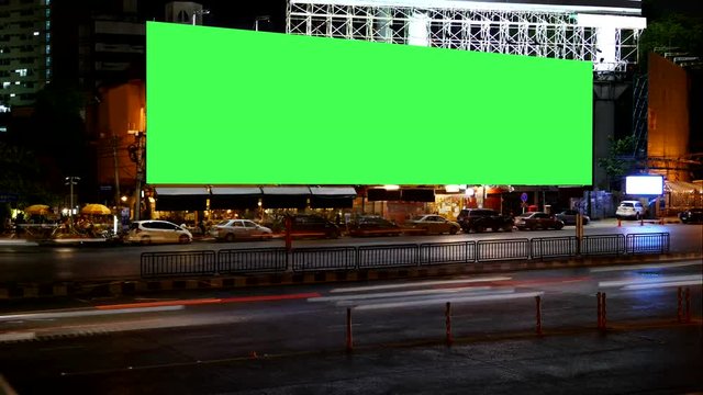 Blank Advertising Billboard green screen beside road with traffic at night, for advertisement, time lapse.