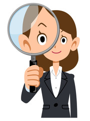 スーツを着た女性が虫眼鏡を持つ
