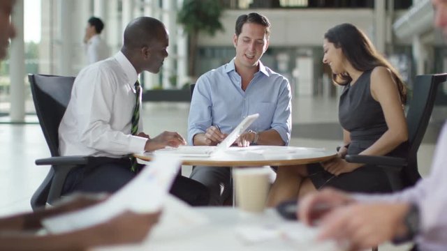 Mixed ethnicity business group chatting in large modern office building