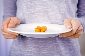 Female hands holding a plate with slices of baby carrots.