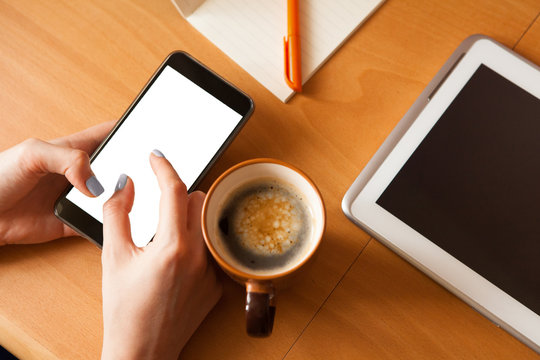 Mobile phone mockup. Female hands with smartphone with copy space on screen and cup of coffee. Fingers zooming in picture on screen. Social network concept.