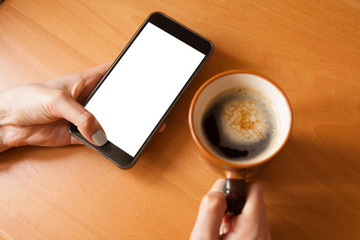 Mobile phone mockup. Female hands with smartphone with copy space on screen and cup of coffee. Mobile phone with blank screen.