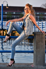Fototapeta na wymiar Attractive young woman sitting on pier enjoying spring warm weather. Active lifestyle concept.